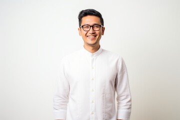 Young handsome Indian man wearing glasses and a white shirt standing and smiling