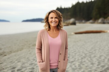 Portrait of smiling middle aged woman standing on beach looking at camera