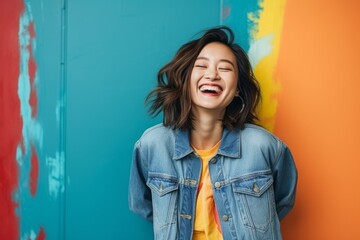 Fototapeta premium Image of a beautiful happy young asian woman posing isolated over colorful wall background.