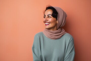 Fototapeta premium Portrait of a beautiful young woman wearing a headscarf against orange background
