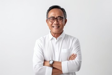Portrait of happy senior Asian man wearing glasses and white shirt standing with arms crossed over white background.