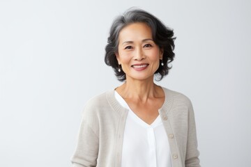 Fototapeta premium Portrait of a smiling mature asian businesswoman standing over white background