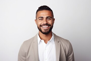 Portrait of handsome young man smiling and looking at camera while standing against grey background