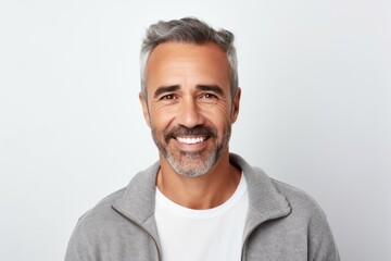 Portrait of handsome mature man looking at camera and smiling while standing against white background