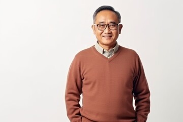 Portrait of a happy mature asian man in eyeglasses standing against white background