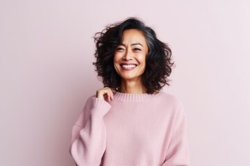 Fototapeta premium Portrait of a smiling young woman in a pink sweater on a pink background
