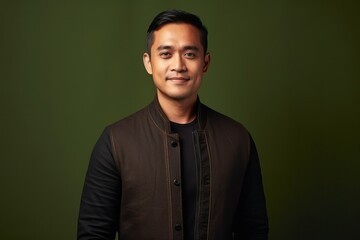 Obraz premium Portrait of a smiling young asian man in black jacket against green background