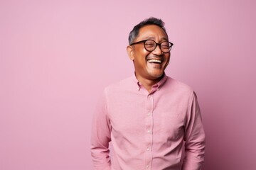 Obraz premium Portrait of a smiling asian man in glasses on a pink background