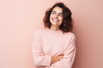Fototapeta premium Portrait of a happy young woman standing with arms folded isolated over pink background