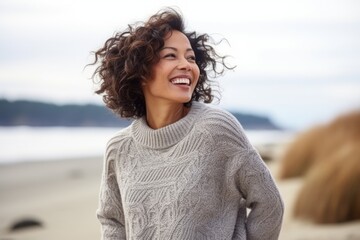 Close up portrait of a beautiful young woman smiling on the beach, wearing sweater