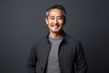 Portrait of happy asian man looking at camera on grey background