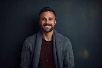 Portrait of a handsome young man smiling at camera while standing against black background