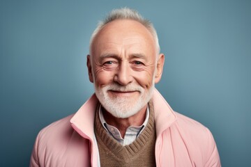 Obraz premium Portrait of a senior man in a pink jacket on a blue background