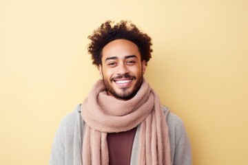 Fototapeta na wymiar Portrait of a smiling young man in scarf and sweater against yellow background