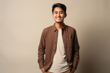 Fototapeta premium Portrait of a happy young indian man standing against gray background