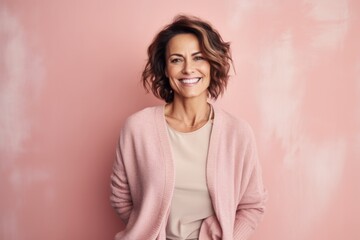 Obraz premium Portrait of beautiful smiling woman in pink sweater on pink background.