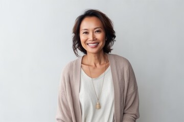 Fototapeta premium Portrait of a smiling middle-aged Asian woman standing against grey background