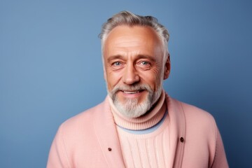 Obraz premium Portrait of a senior man with grey hair and beard in a pink sweater on a blue background