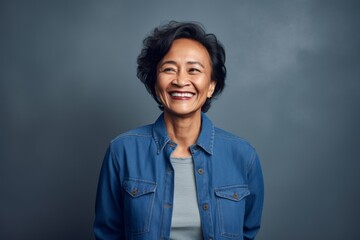 Fototapeta premium Portrait of a smiling middle-aged Asian woman standing against grey background