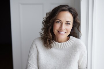 Portrait of smiling woman standing by window at home in the living room