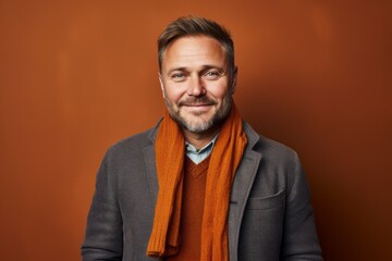 Obraz premium Portrait of a handsome mature man with an orange scarf on a brown background
