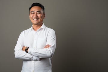 Portrait of happy asian man with arms crossed against gray background
