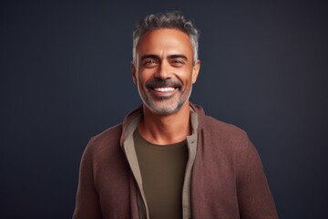 Handsome middle-aged man looking at camera and smiling while standing against grey background