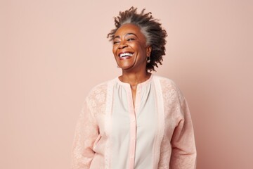 Fototapeta premium Portrait of a beautiful african american woman laughing against pink background