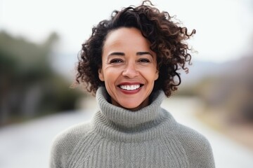 Portrait of smiling woman in sweater looking at camera on blurred background