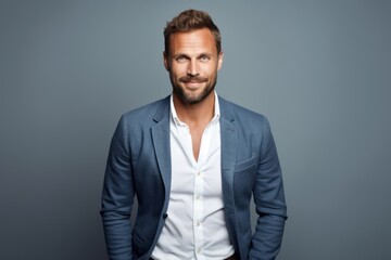 Fototapeta premium Handsome young man in jacket looking at camera and smiling while standing against grey background
