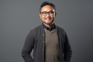 Obraz premium indian man in eyeglasses smiling at camera isolated on grey