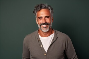 Fototapeta premium Portrait of a handsome mature man smiling at the camera while standing against a green background