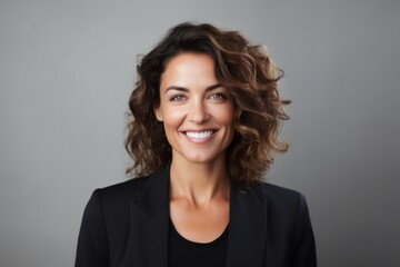 Fototapeta premium Portrait of a smiling businesswoman with curly hair against grey background