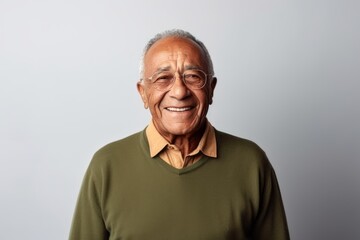 Portrait of a happy senior man smiling at the camera while standing against grey background