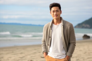young asian man standing on the beach looking to the camera smiling