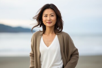 Portrait of young beautiful Asian woman smiling on the beach. She is wearing casual clothes.
