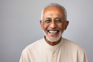Portrait of smiling Indian senior man in eyeglasses, isolated on grey background