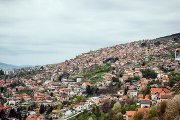 Fototapeta na wymiar Panoramic view of the spring city of Sarajevo, Bosnia and Herzegovina. A trip to a European city in the mountains with orange roofs