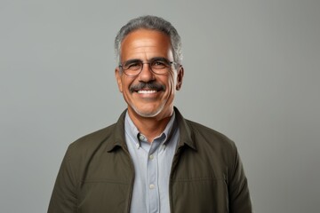 Fototapeta premium Portrait of a smiling Indian mature man with glasses on grey background