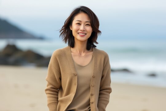 Smiling asian woman standing on the beach with the sea in the background
