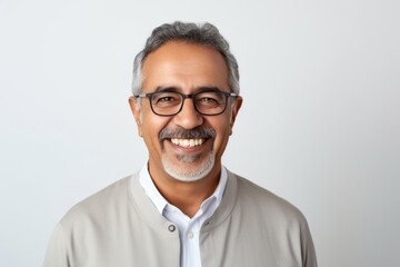 Portrait of happy mature Indian man in eyeglasses smiling at camera