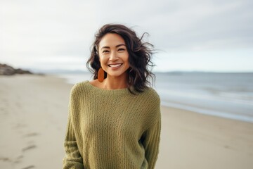Portrait of a smiling young woman in sweater standing on the beach
