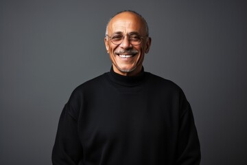 Obraz premium Portrait of a smiling senior man in a black turtleneck. Isolated on grey background.