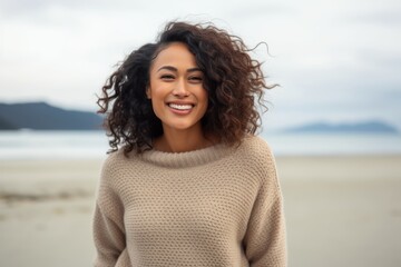 Portrait of beautiful young woman with curly hair smiling on the beach