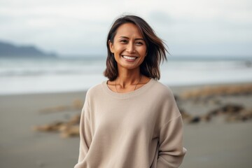 Portrait of a smiling young woman standing on the beach and looking at camera