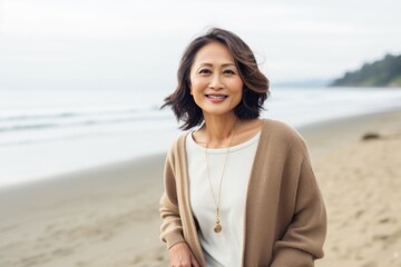 Portrait of a happy mature woman standing on the beach and looking at camera