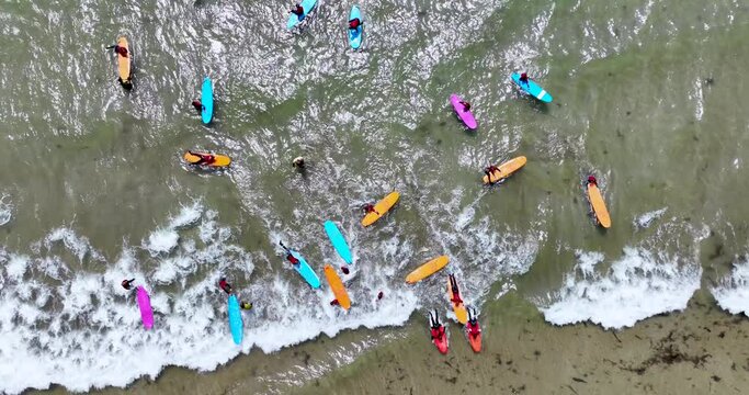 An overhead view of colourful surfboards, surfers gathered to ride 4k
