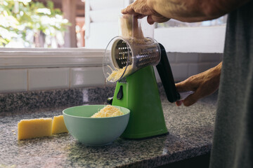 Unrecognizable Elderly woman Using a Modern Manual Grater That Facilitates her Work in the kitchen....