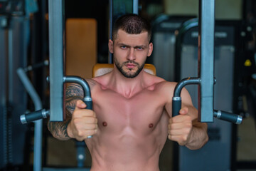 Fototapeta na wymiar Muscular hunk with posing in gym. Fitness male model near gym equipment. Young muscular man workout. Sport man with strong muscular torso in gym. Sport and motivation. Exercises with weight.