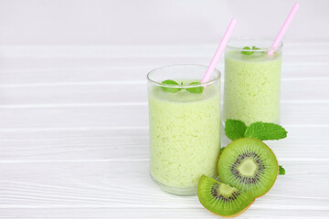 Kiwi yogurt fruit juice smoothie and green kiwi juice drink healthy, delicious taste in a glass for weight loss on a white wooden background.
